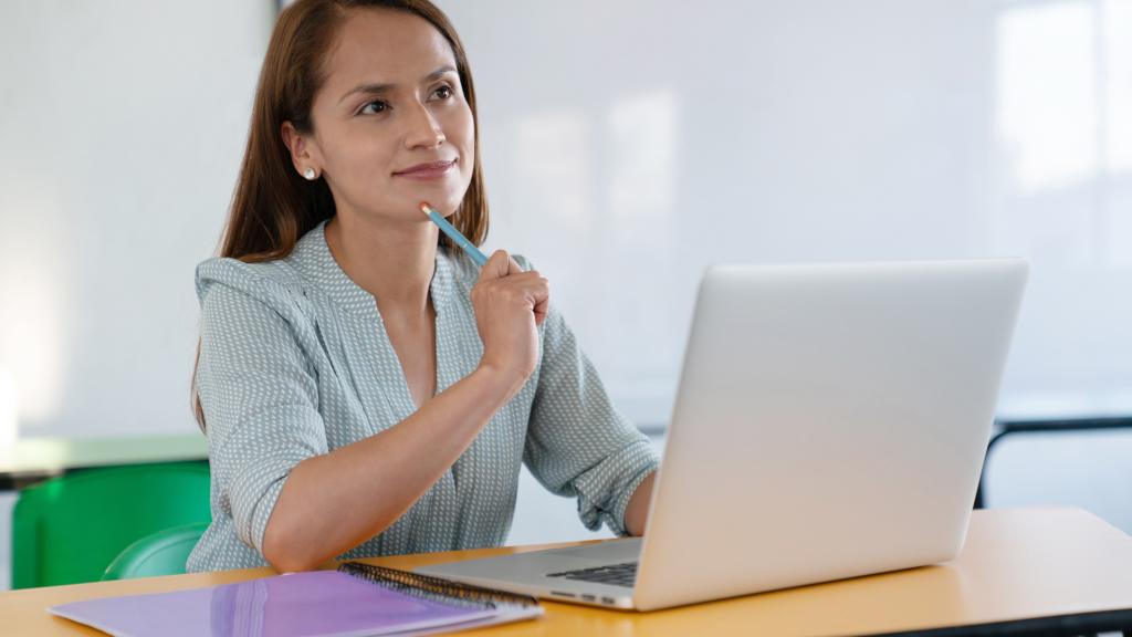 A woman thinking while working on a laptop