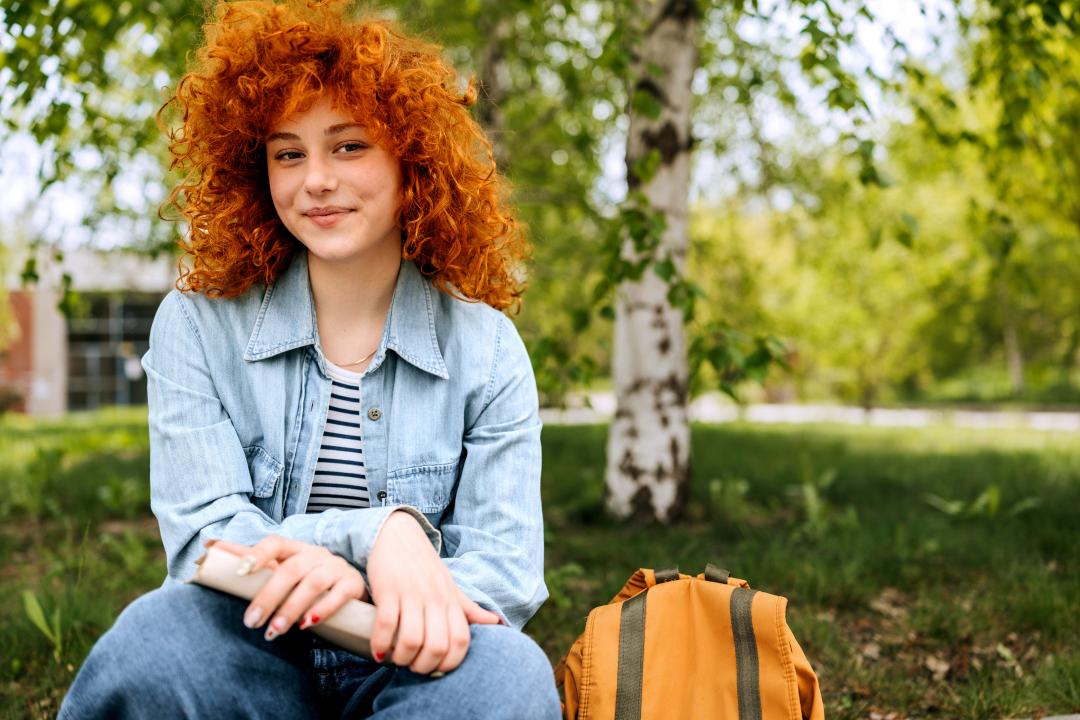 Girl sitting on ledge with book.
