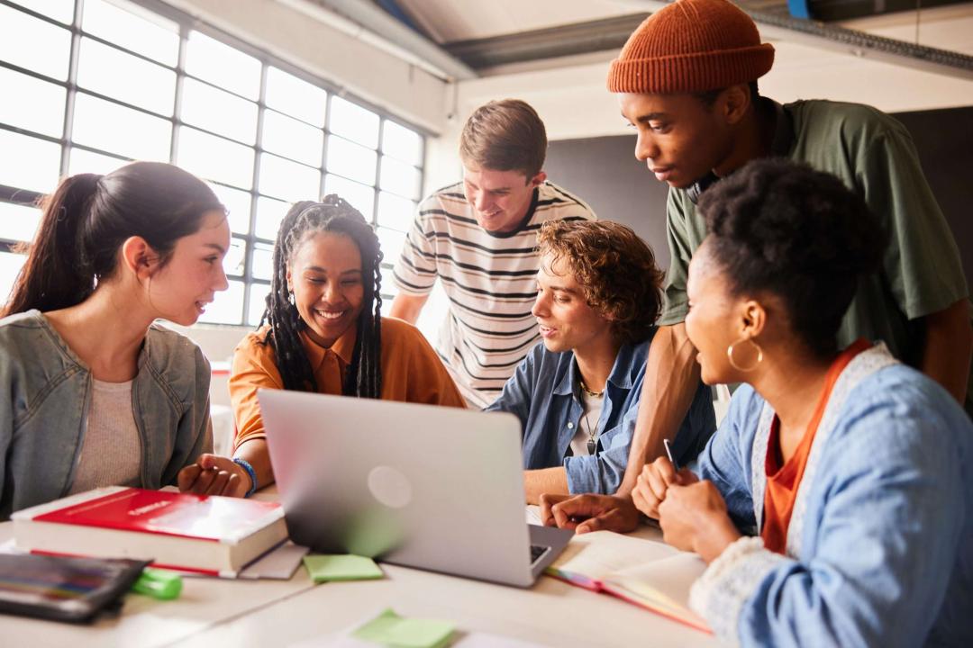 Students gathering around a laptop