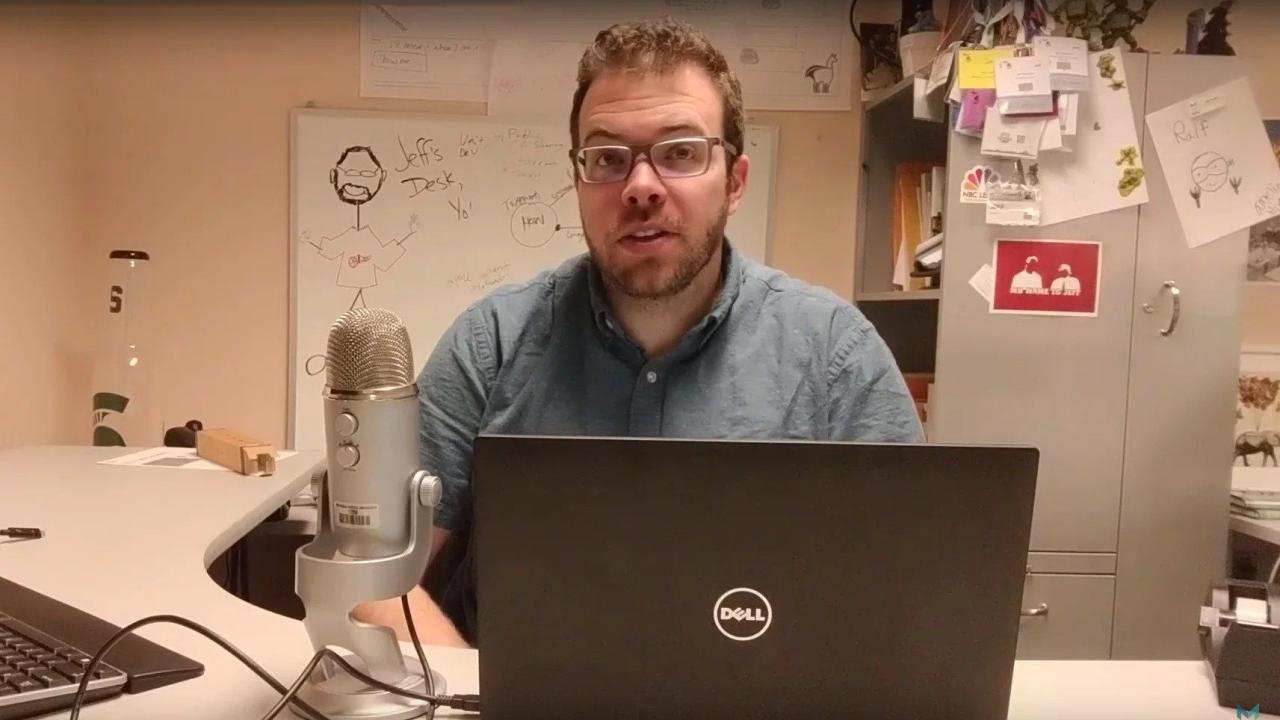 Jeff Gerlach sitting at his desk with a laptop and microphone