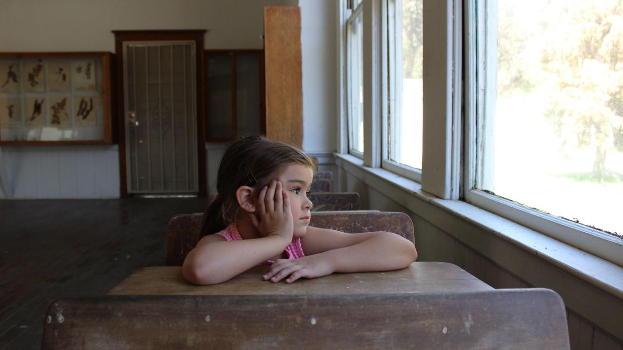 Child staring out a window in a classroom