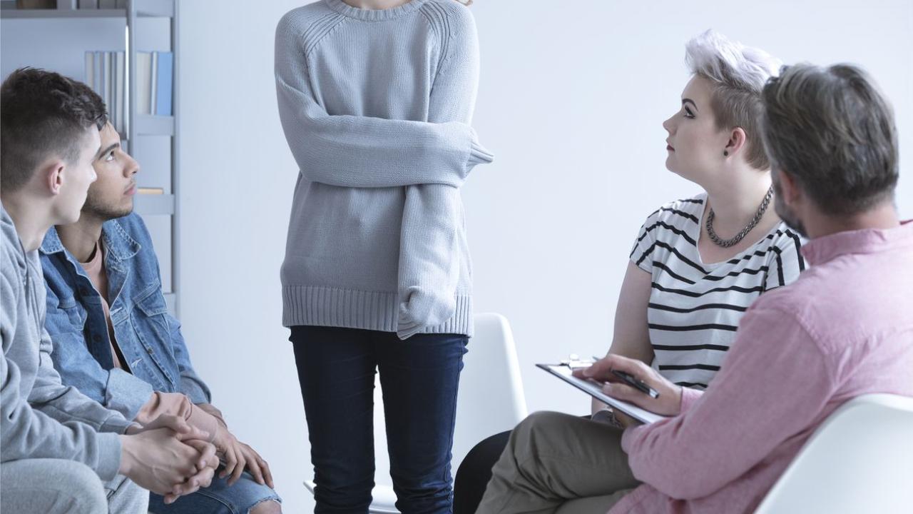 Ashamed girl sharing her issues with others, at group therapy