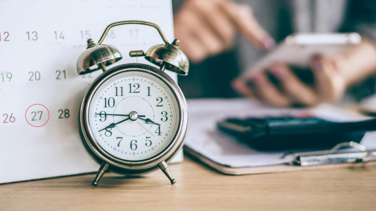 alarm clock in front of calender with circled deadline