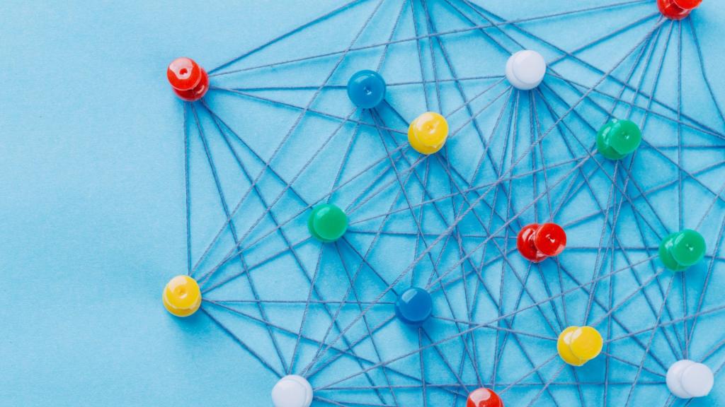 Small network of pins (Thumbtack)and string, An arrangement of colorful pins linked together with string on a pale blue background suggesting a network of connections.