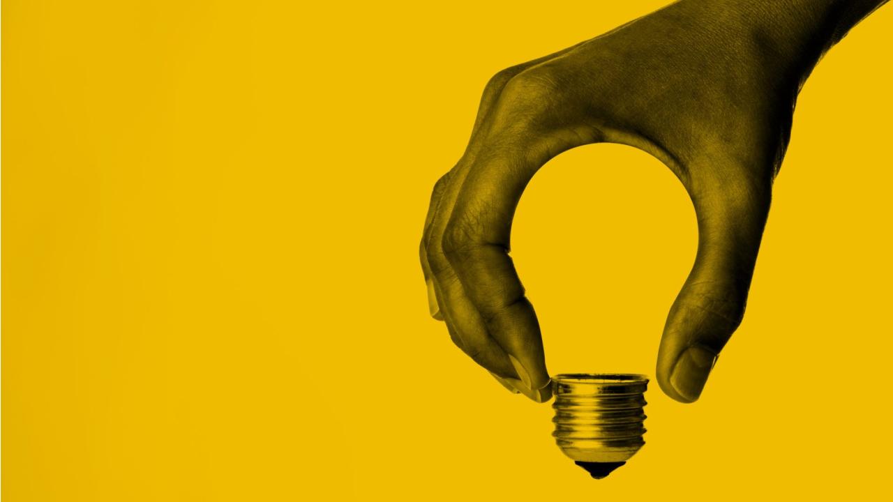 Image of hand formed in the shape of a lightbulb against yellow background