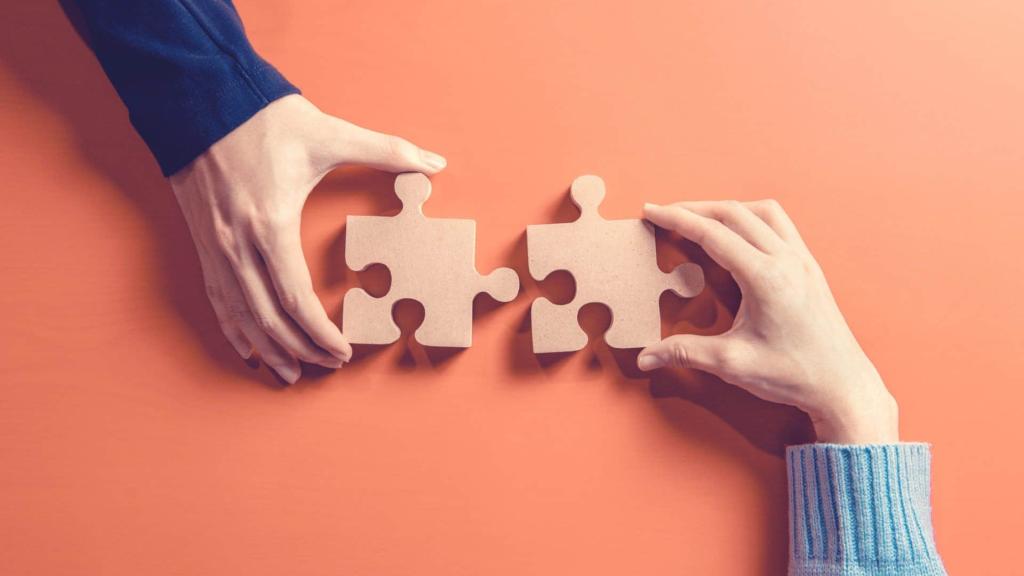 two hands pushing puzzle pieces together
