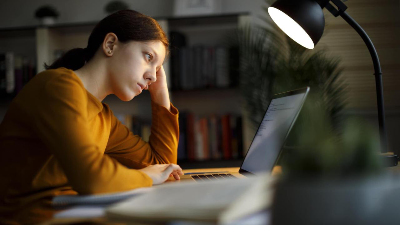 Worried teenage girl studying late at home