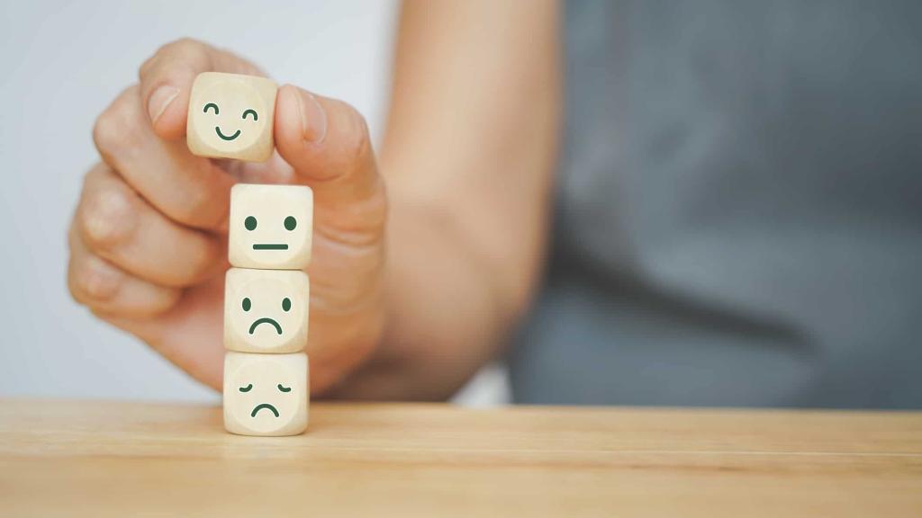senior human hand selected happy face wood cube and others on green background for customer service evaluation, feedback, satisfaction survey or mental heath concept