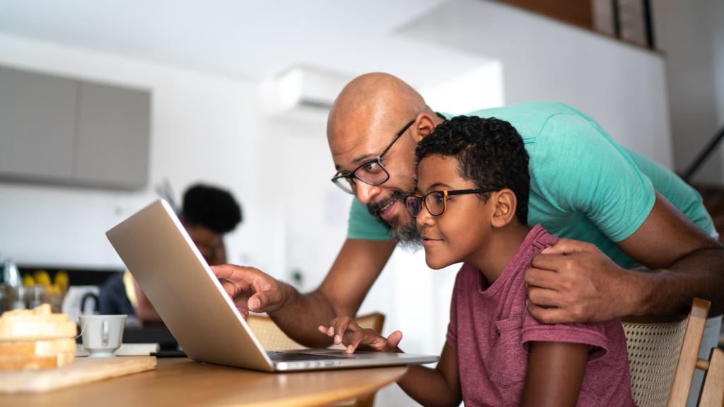 Father encouraging son on homeschooling or doing a video call/watching a movie