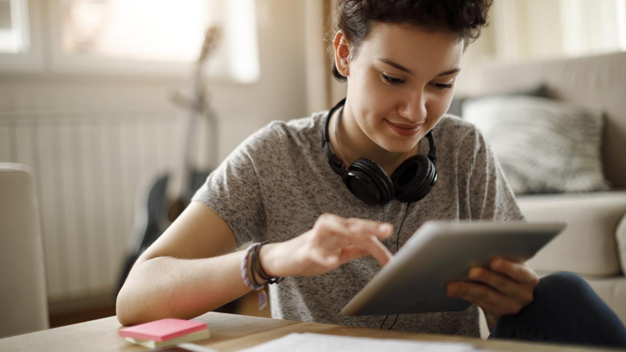 Smiling young woman using digital tablet at home