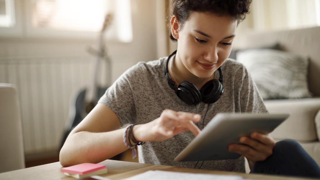Smiling young woman using digital tablet at home