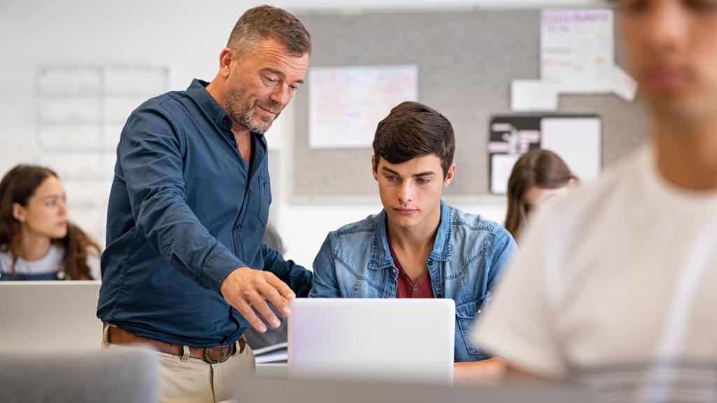 Professor helping student during computer class
