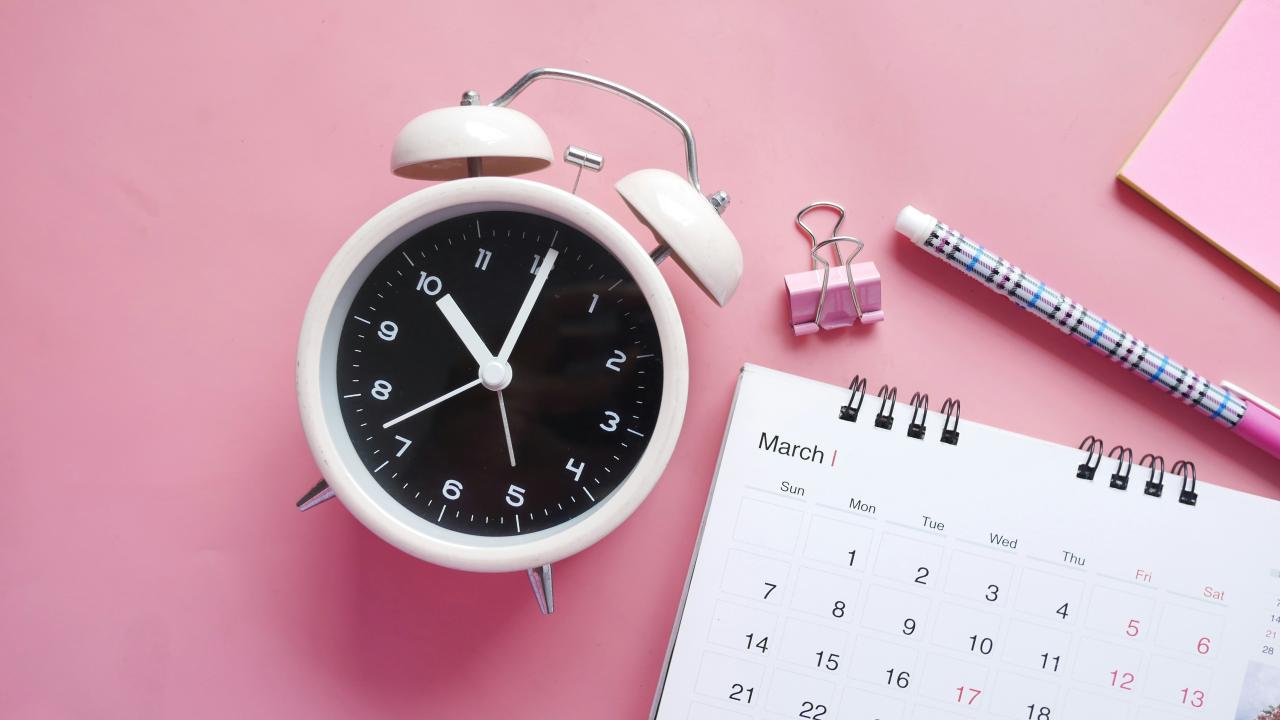 image of an analog block on a pink background with a March calendar