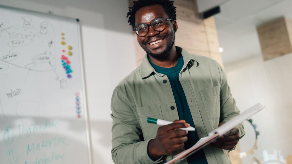 Smiling man holding notebook and marker in office meeting room