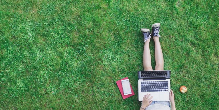Girl using laptop in grass
