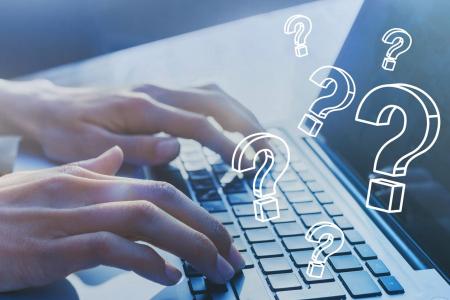 person using a laptop with question marks