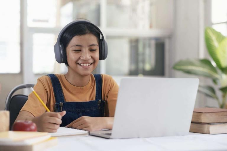Happy asian girl learning online at home