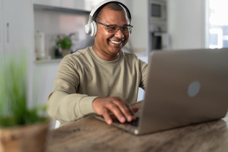 Happy senior man having fun doing using laptop at home - Technology and smart working concept