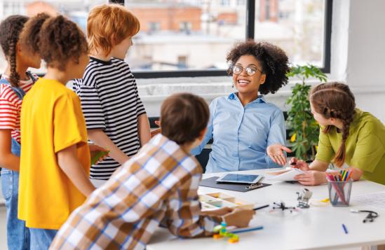 African american teacher smiling and helps students during lesson in bright classroom