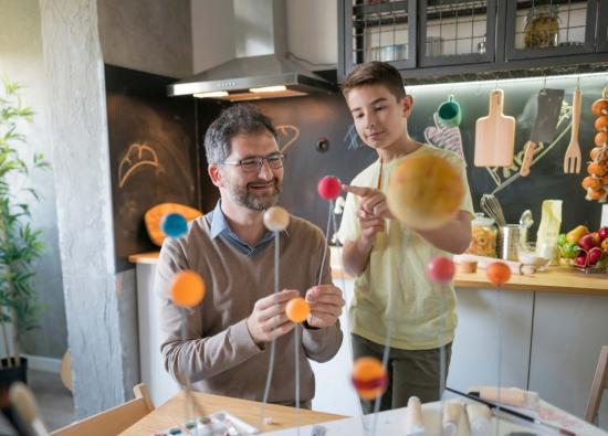 Father and son working on a science project together in a kitchen