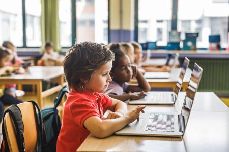 Elementary schoolboy using laptop on a class in the classroom.