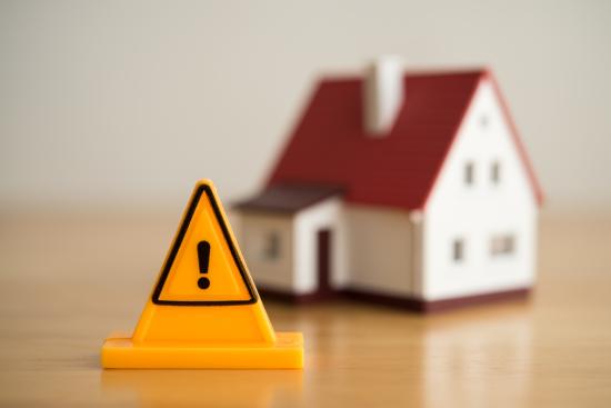 Emergency notification warning sign label with model house background.
