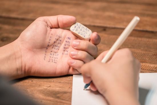 A student writes notes on their palm