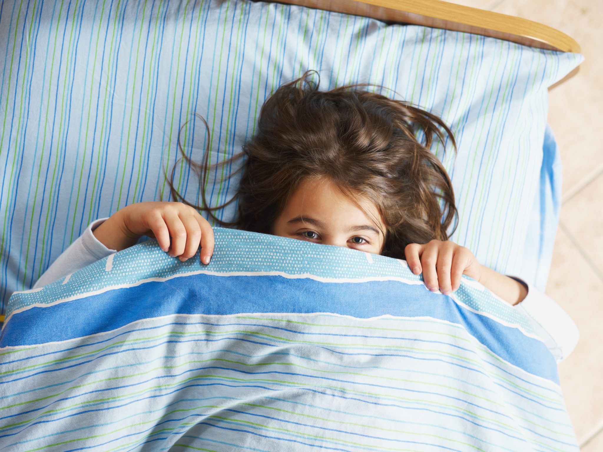 Girl under covers, looking at camera. 