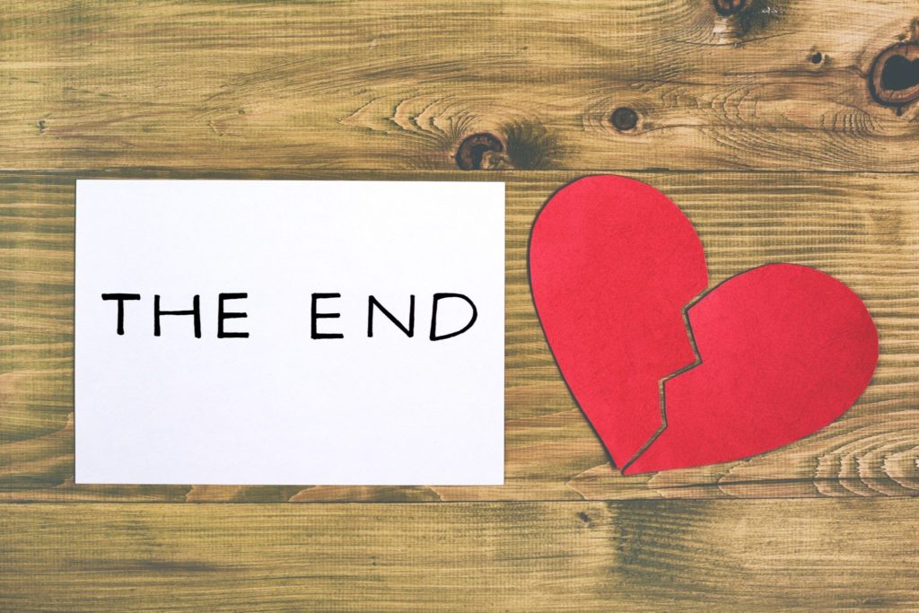 Paper letter with "The End" written on it, with a broken paper heart next to it