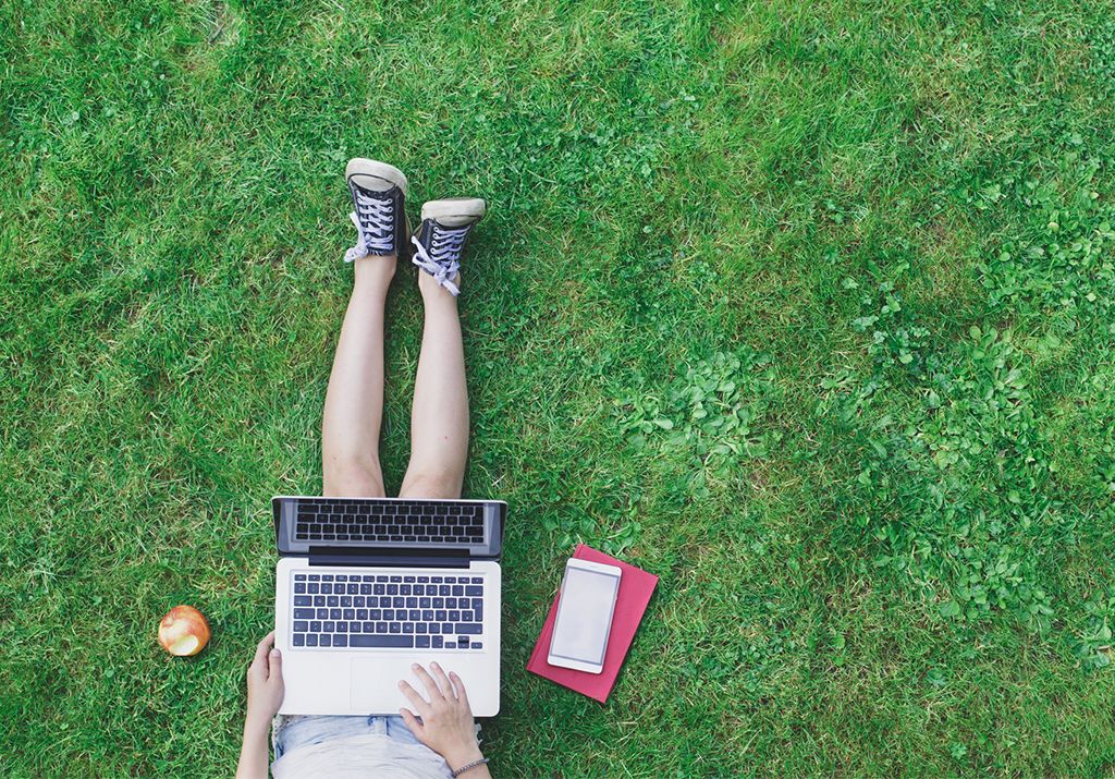 Student sitting on grass using a laptop