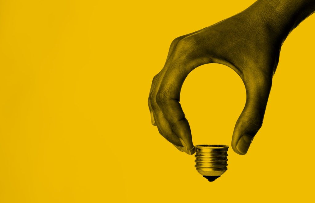 Image of hand formed in the shape of a lightbulb against yellow background